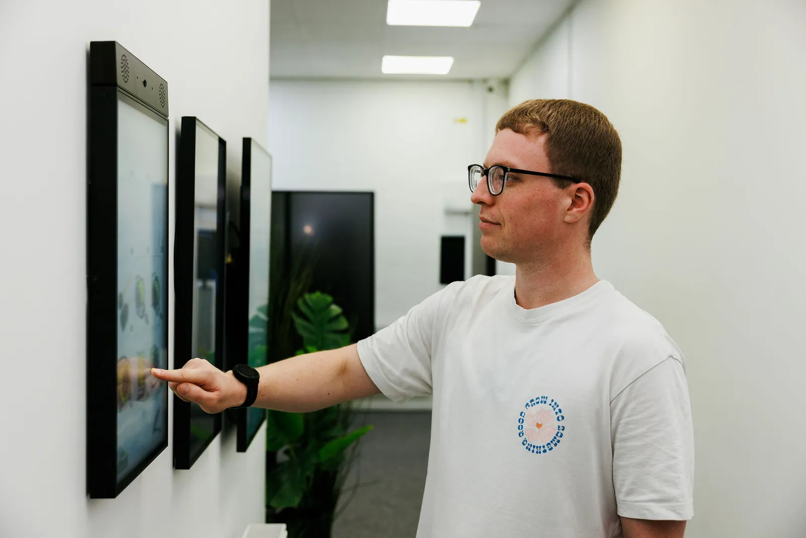A visitor pointing at one of a row of wall-mounted RAVO kiosks
